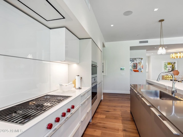 kitchen featuring a sink, gas stovetop, modern cabinets, wood finished floors, and white cabinets