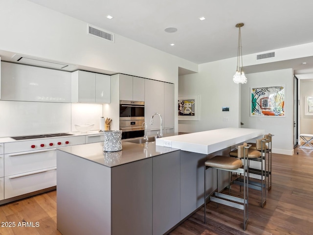 kitchen with modern cabinets, white cabinetry, light wood finished floors, a breakfast bar area, and recessed lighting