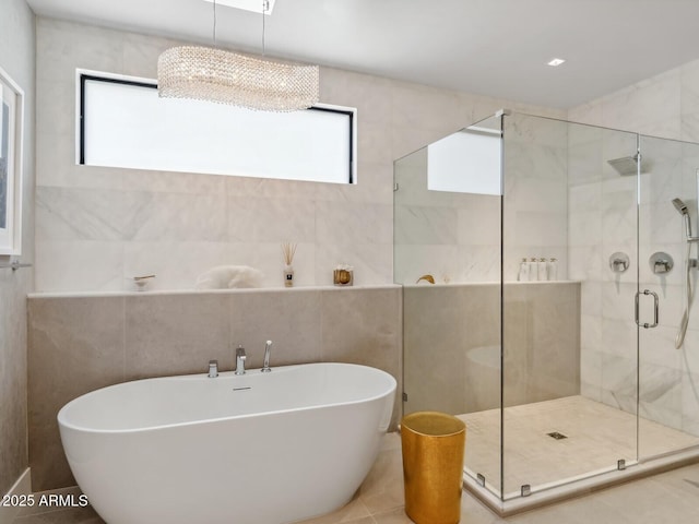bathroom with a soaking tub, a shower stall, and tile walls