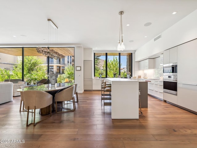 kitchen with modern cabinets, white cabinetry, a kitchen bar, light countertops, and a center island