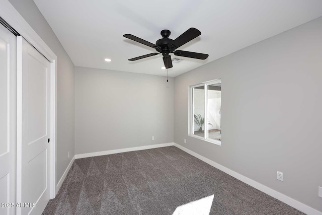 unfurnished bedroom with ceiling fan, dark carpet, and a closet