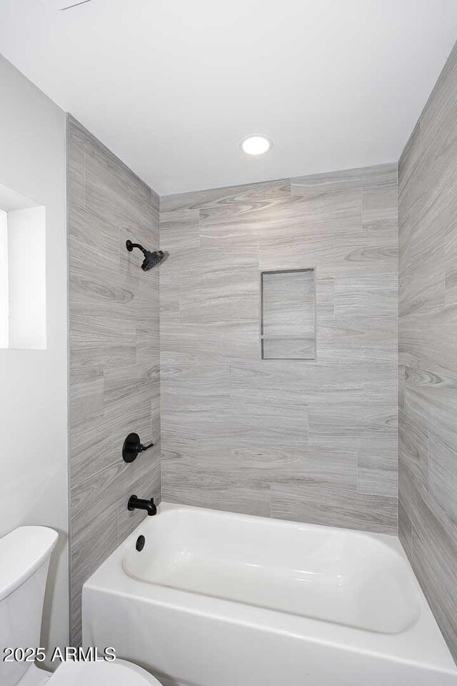 bathroom featuring tiled shower / bath and toilet