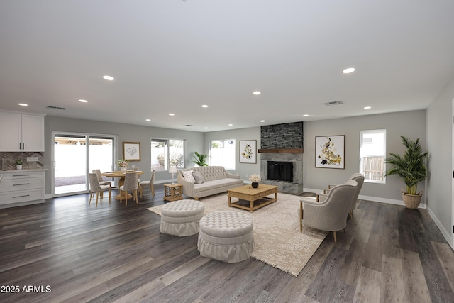 living room with a large fireplace, plenty of natural light, and dark hardwood / wood-style floors