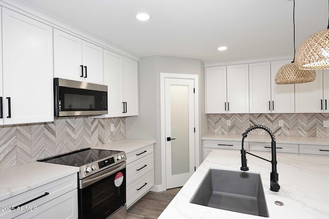 kitchen featuring decorative light fixtures, sink, white cabinets, stainless steel appliances, and light stone countertops