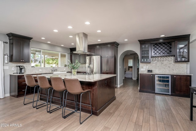 kitchen featuring wall chimney range hood, wine cooler, backsplash, stainless steel fridge with ice dispenser, and light hardwood / wood-style floors