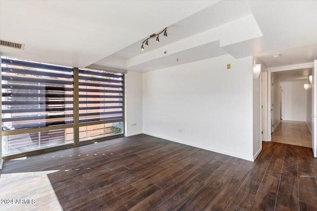 empty room featuring track lighting and dark wood-type flooring