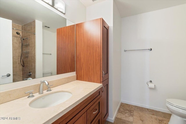 bathroom featuring tiled shower, vanity, and toilet