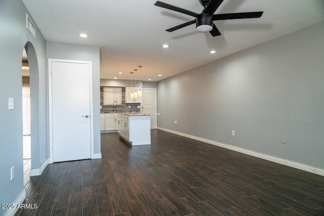 unfurnished living room with dark wood-type flooring, sink, and ceiling fan