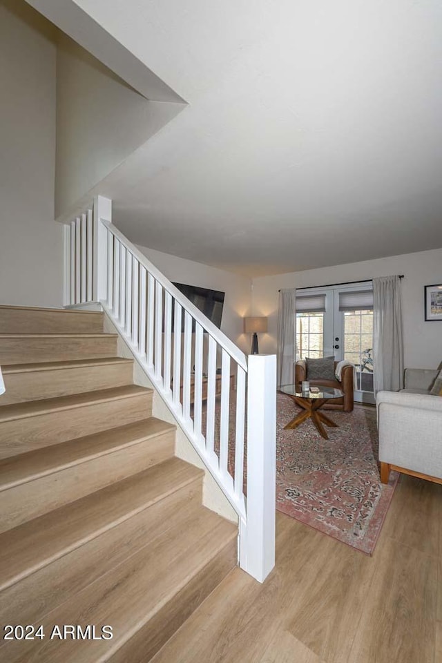 stairway with hardwood / wood-style floors and french doors