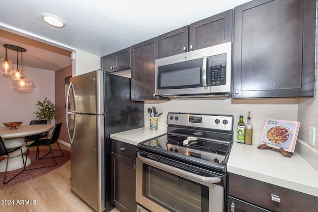 kitchen featuring dark brown cabinets, appliances with stainless steel finishes, hanging light fixtures, and light hardwood / wood-style floors