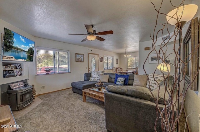 carpeted living room with ceiling fan with notable chandelier, a textured ceiling, and a wood stove