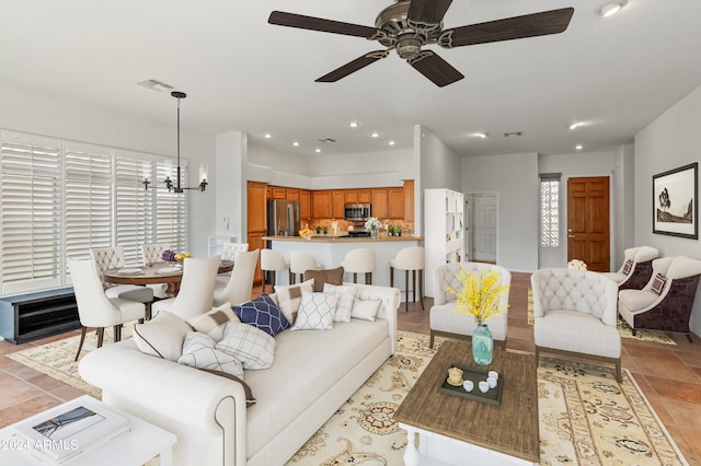 living room with ceiling fan with notable chandelier and light tile patterned floors