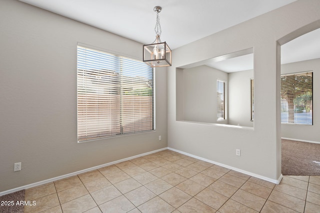 empty room with light tile patterned floors and a notable chandelier