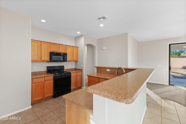 kitchen with light tile patterned flooring, black appliances, a kitchen island with sink, and light stone countertops