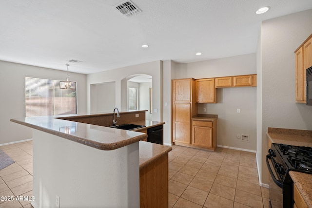 kitchen with black appliances, light brown cabinetry, a kitchen island with sink, sink, and decorative light fixtures