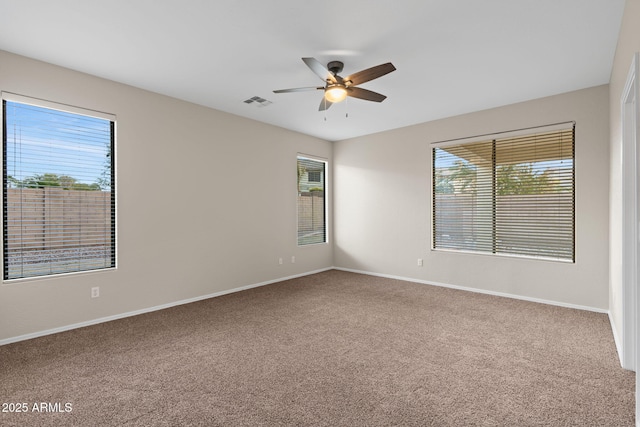 spare room featuring ceiling fan, carpet, and a healthy amount of sunlight