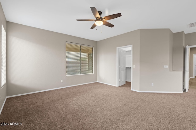 unfurnished bedroom featuring carpet, a closet, ceiling fan, and a walk in closet