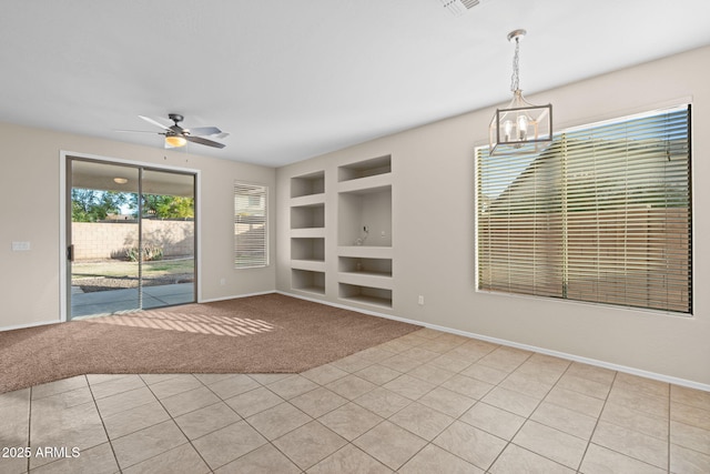 unfurnished living room with ceiling fan with notable chandelier, light tile patterned floors, and built in features