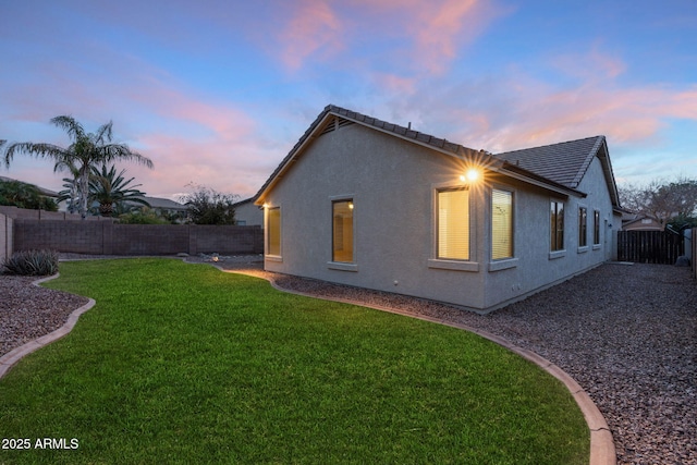 property exterior at dusk featuring a yard