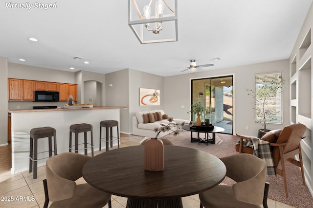 dining room featuring ceiling fan with notable chandelier and light tile patterned flooring