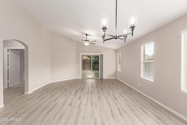 spare room featuring ceiling fan with notable chandelier, light hardwood / wood-style flooring, and lofted ceiling