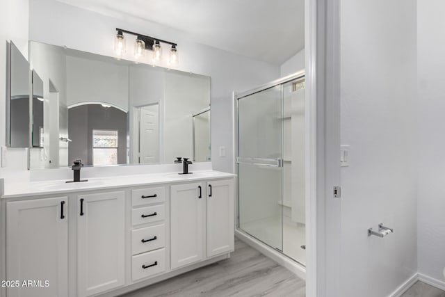 bathroom featuring hardwood / wood-style floors, a shower with door, and vanity