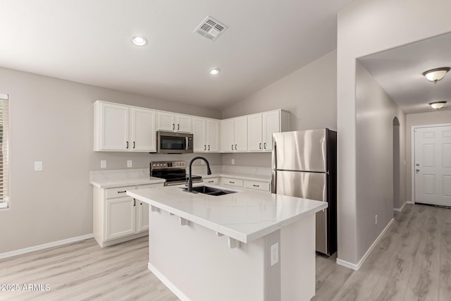 kitchen featuring appliances with stainless steel finishes, white cabinetry, an island with sink, sink, and light wood-type flooring