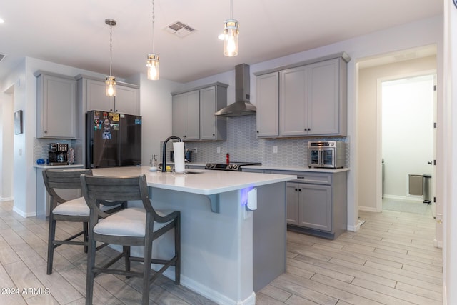 kitchen featuring black fridge, gray cabinets, sink, and wall chimney range hood