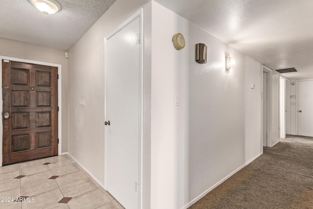 hall featuring a textured ceiling and light colored carpet