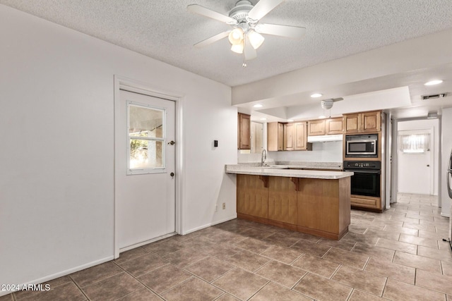 kitchen with kitchen peninsula, black oven, stainless steel microwave, and plenty of natural light