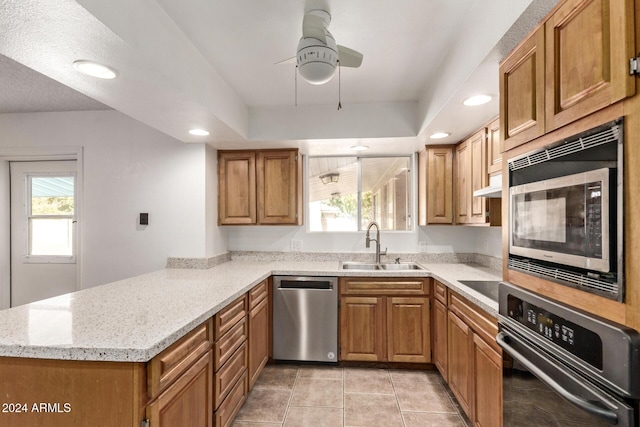 kitchen with kitchen peninsula, sink, light tile patterned floors, and stainless steel appliances