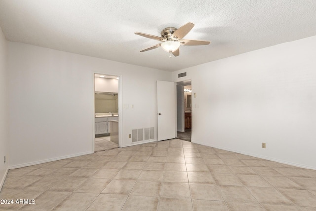 unfurnished bedroom featuring a textured ceiling, ceiling fan, light tile patterned floors, a spacious closet, and a closet