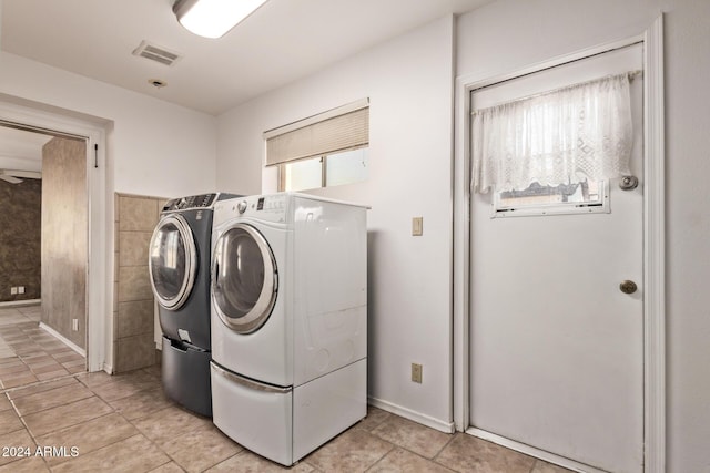 washroom featuring washer and clothes dryer, light tile patterned flooring, and tile walls