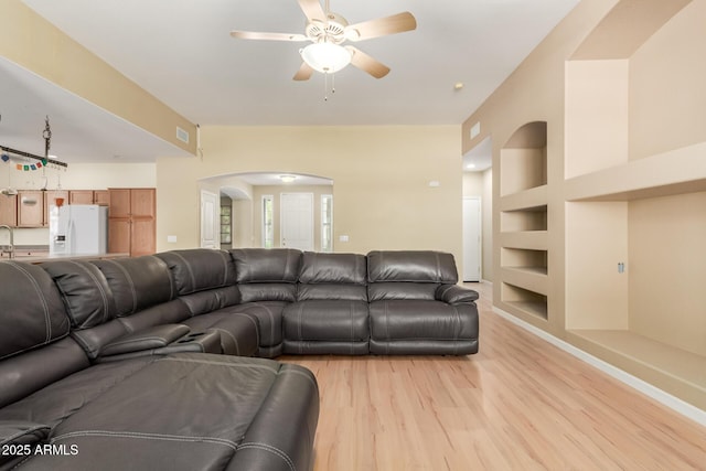 8256 W Bloomfield Rd, Peoria, AZ 85381 - living area featuring arched walkways, light wood-type flooring, built in shelves, and a ceiling fan