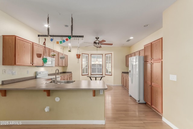 8256 W Bloomfield Rd, Peoria, AZ 85381 - kitchen featuring white appliances, a peninsula, a ceiling fan, light wood-style floors, and a sink