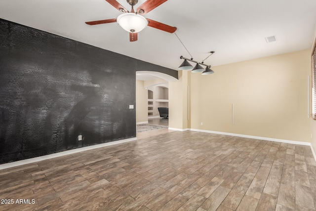 8256 W Bloomfield Rd, Peoria, AZ 85381 - empty room featuring arched walkways, a ceiling fan, wood finished floors, and baseboards