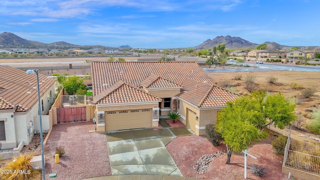 view of front of home with fence, driveway, stucco siding, a tile roof, and a mountain view