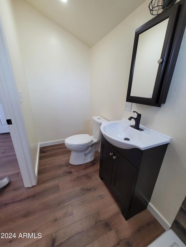 bathroom with vanity, toilet, and hardwood / wood-style floors