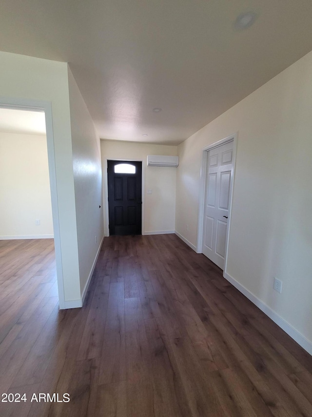 foyer entrance with dark wood-type flooring and a wall unit AC