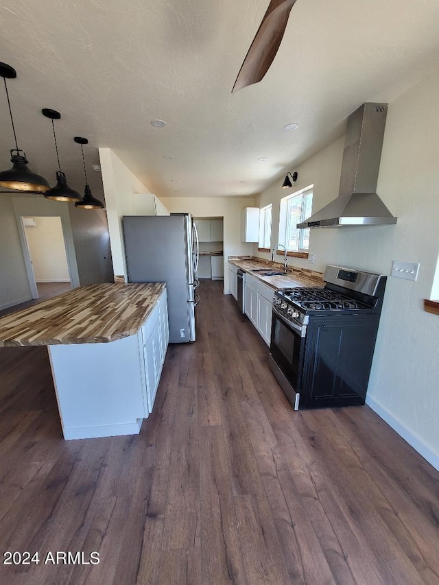 kitchen featuring pendant lighting, white cabinetry, stainless steel appliances, dark wood-type flooring, and wall chimney exhaust hood