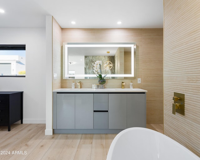 bathroom with hardwood / wood-style floors, a tub, vanity, and tasteful backsplash