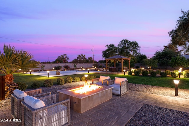 patio terrace at dusk featuring a yard, a gazebo, and an outdoor fire pit