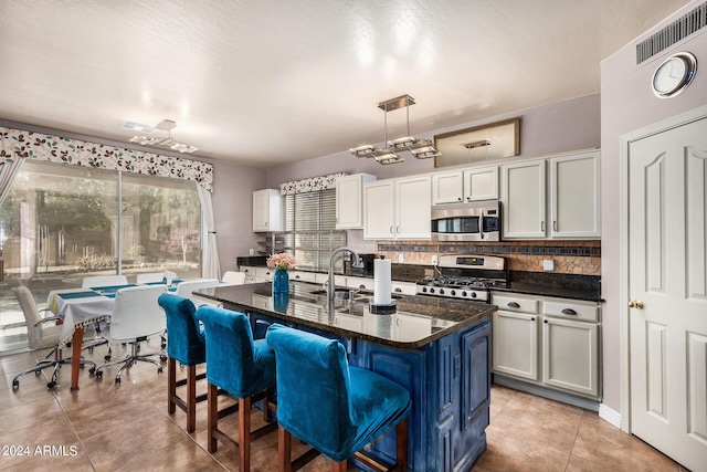 kitchen with pendant lighting, light tile patterned flooring, a kitchen island with sink, a kitchen breakfast bar, and stainless steel appliances