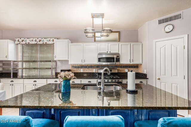 kitchen with decorative light fixtures, dark stone countertops, a spacious island, a kitchen bar, and stainless steel appliances