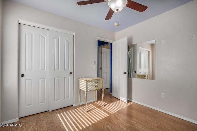 unfurnished bedroom with ceiling fan, a closet, and light wood-type flooring