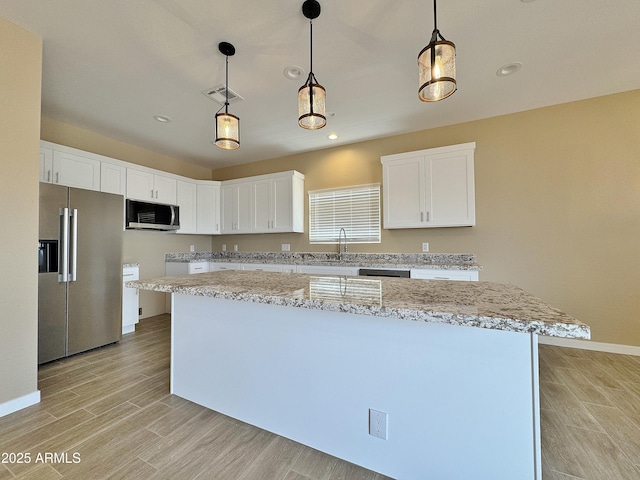 15422 S Sequoia Cir, Arizona City, AZ 85123 - kitchen featuring visible vents, decorative light fixtures, white cabinetry, stainless steel appliances, and light wood-style flooring