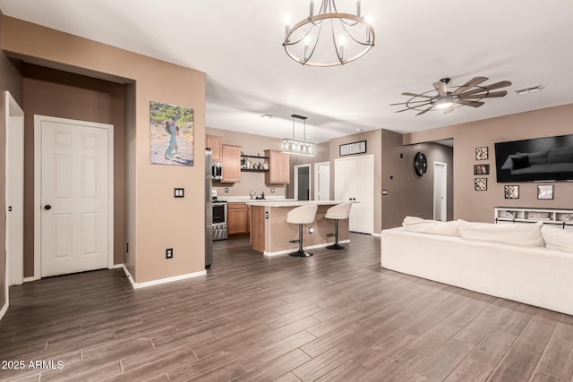 living room featuring ceiling fan with notable chandelier and dark hardwood / wood-style flooring