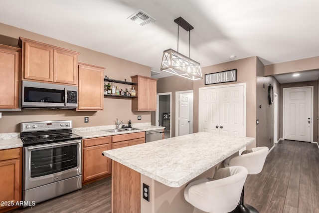 kitchen with sink, stainless steel appliances, hanging light fixtures, and dark wood-type flooring