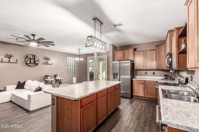 kitchen with sink, a kitchen island, dark hardwood / wood-style floors, decorative light fixtures, and stainless steel appliances