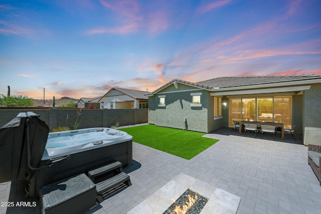 29339 N 135th Dr, Peoria, AZ 85383 - back of property at dusk with a hot tub, a patio area, stucco siding, a tiled roof, and a fire pit